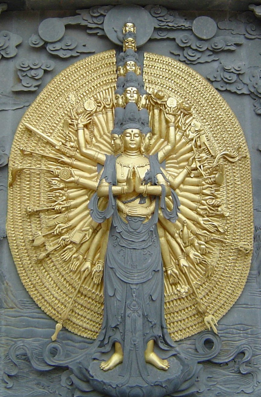 A relief in gold and stone showing bodhisattva that has multiple heads and arms.